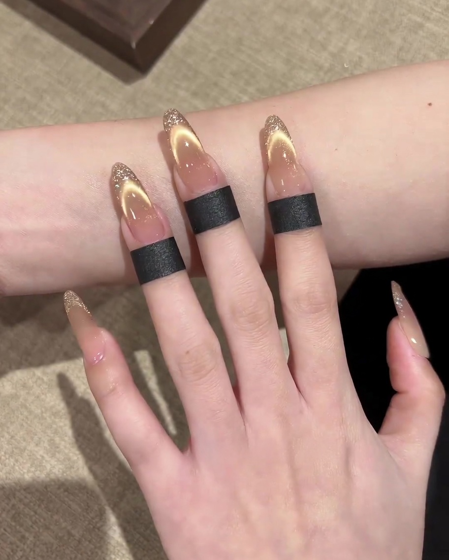 A magnetic tool held parallel over the nail, revealing a broad, glowing gold shimmer line.