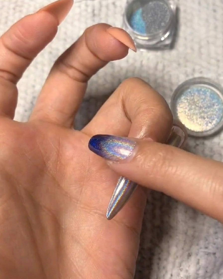 A close-up showing the holographic powder being blended on the nail for an ombre look.