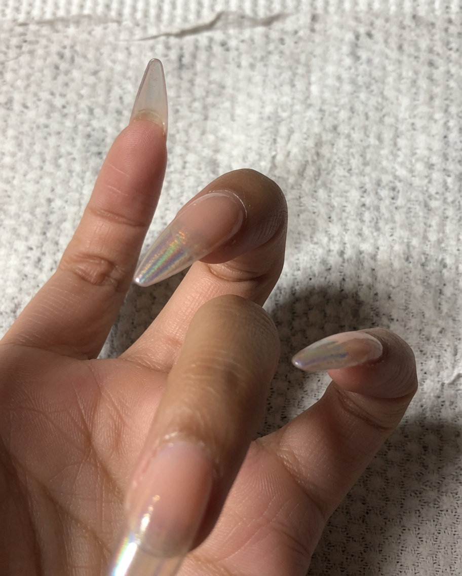 A hand using a small buffer to file the front edge of a fingernail.