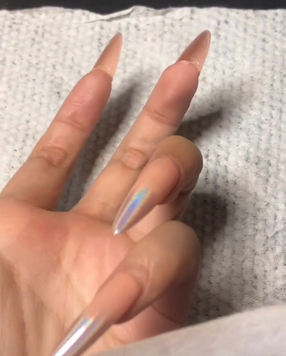 A hand using a small buffer to file the front edge of an index fingernail.