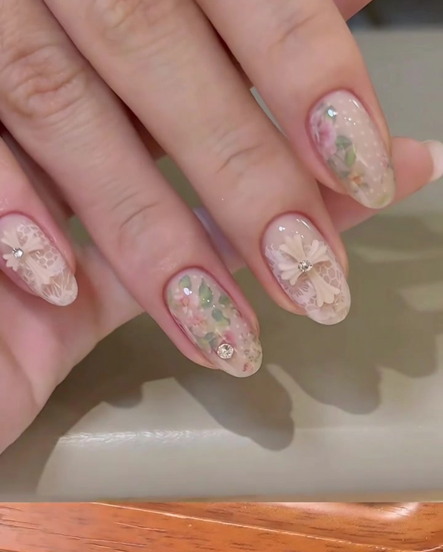 A clear stamper transferring a delicate white lace pattern onto a nude nail.