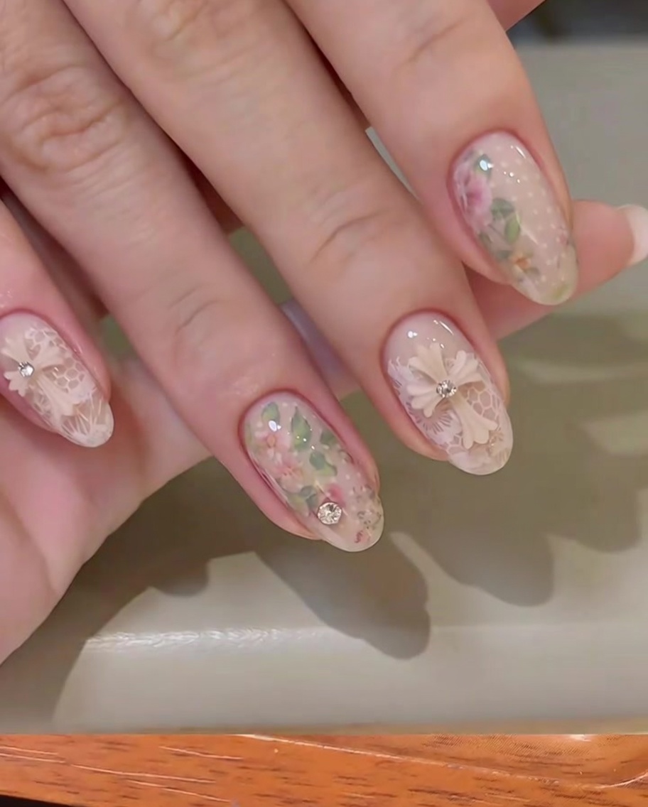 A pair of tweezers holding a 3D bow charm, positioning it onto a nude-colored nail.
