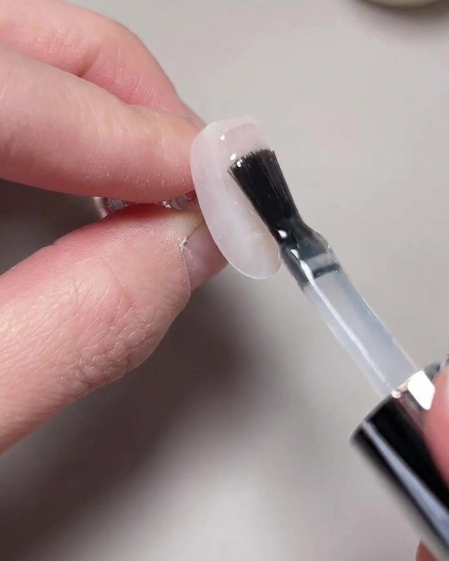 A hand positioned inside a UV/LED nail lamp for curing.