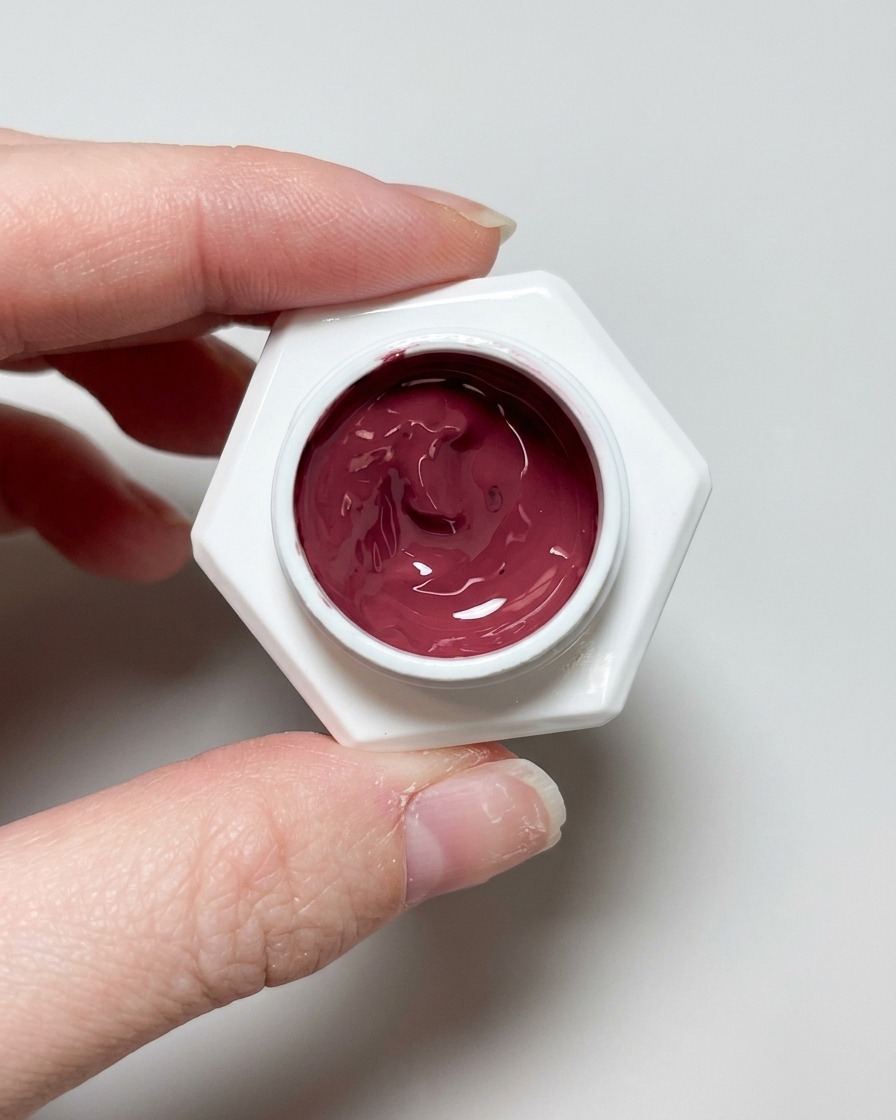 A brush applying a clear, glossy top coat over the finished cat eye nail design.