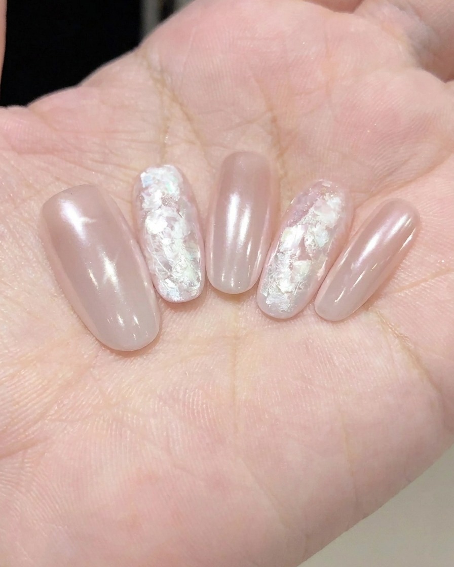 A hand using a lint-free wipe to clean the surface of a finished, cured nail.
