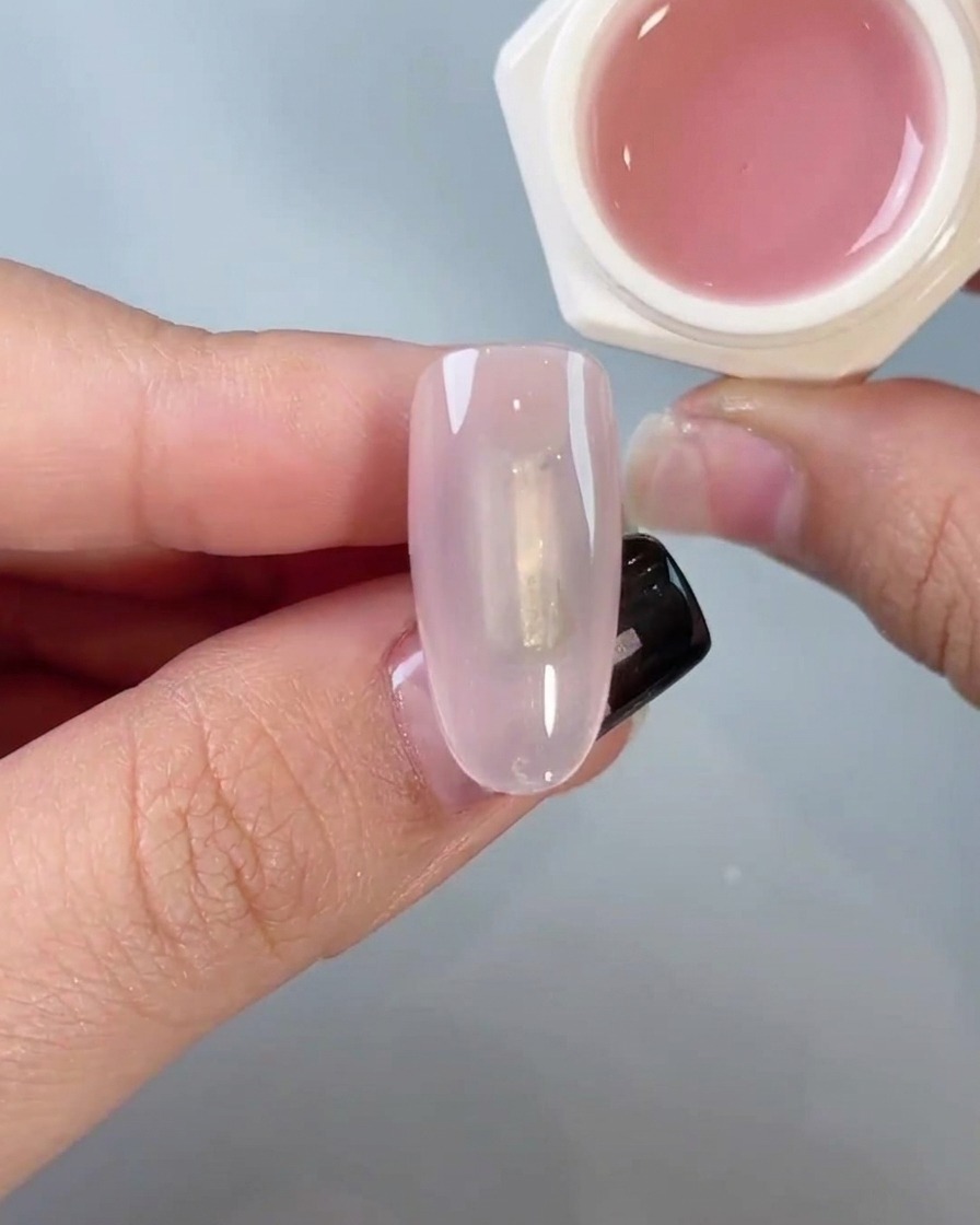 A sponge applicator gently rubbing chrome powder onto a nail to create a mirror finish.