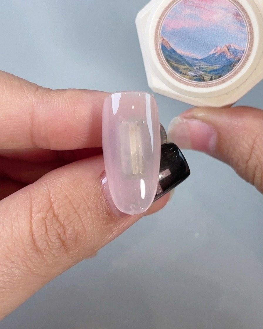 A nail brush applying a clear top coat over a mirror-finished chrome nail.