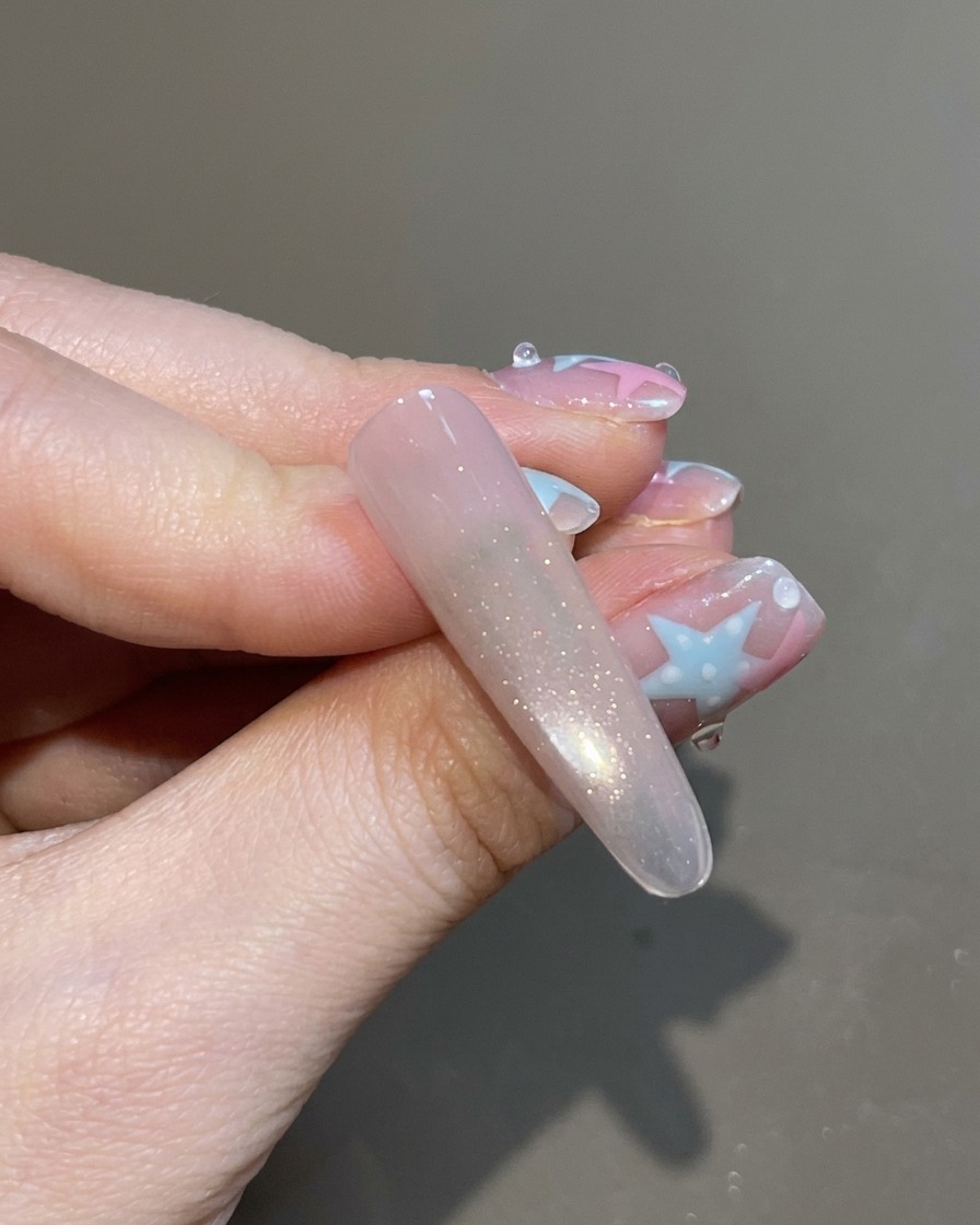 A brush applying a clear top coat over the fully magnetized and shimmering cat-eye nail.