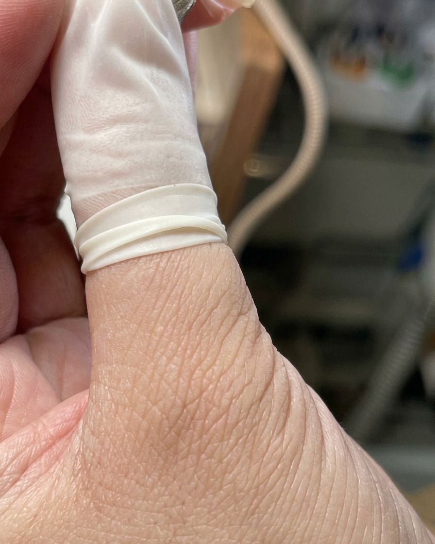 A hand resting inside a professional UV/LED nail lamp with the light activated.