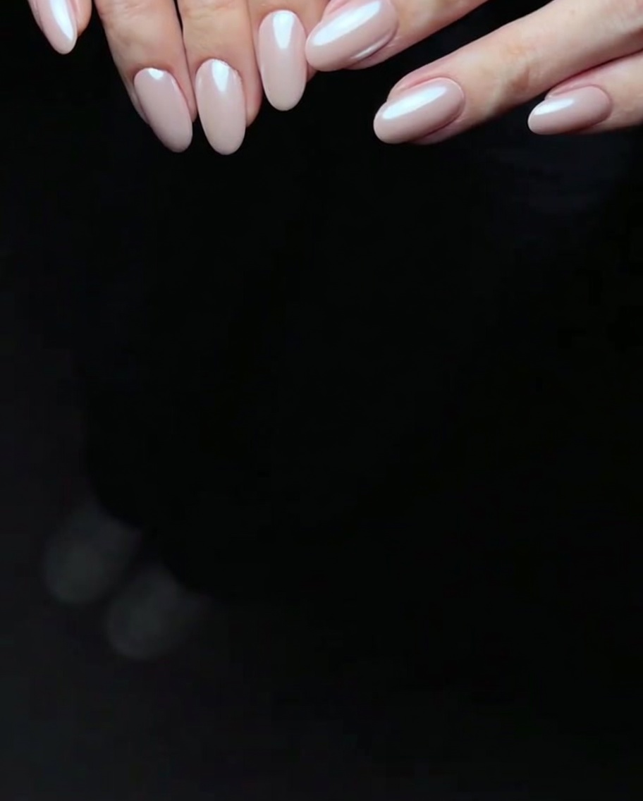 A brush applying a second, slightly deeper layer of pink gel polish to a fingernail.