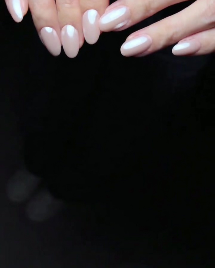 Fingernails with two coats of pink gel polish curing inside an LED lamp.