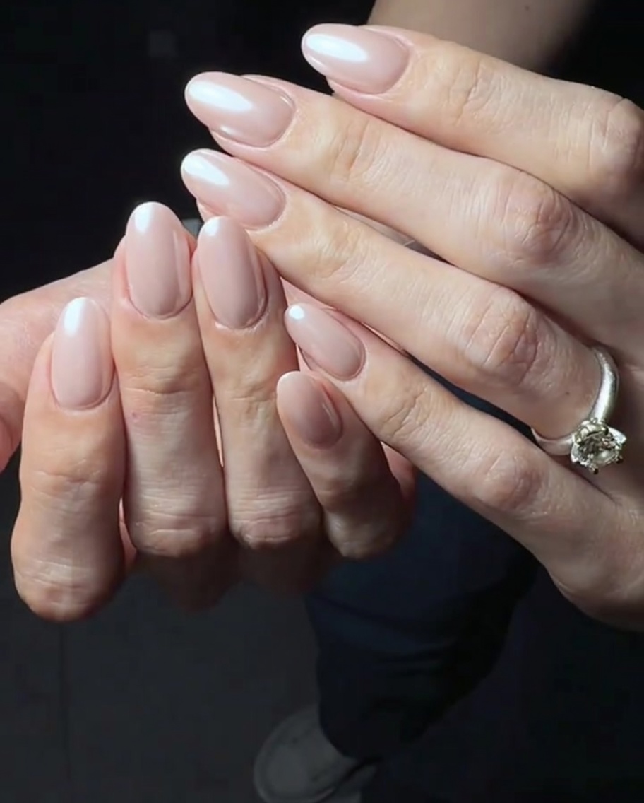 A thin, glossy layer of top coat being applied over the pink gel base.