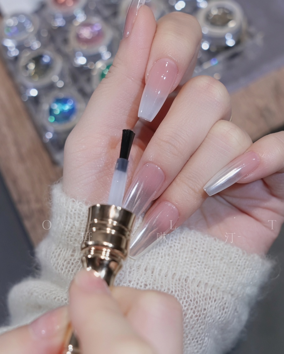 A brush applying clear top coat over the finished gradient nail.