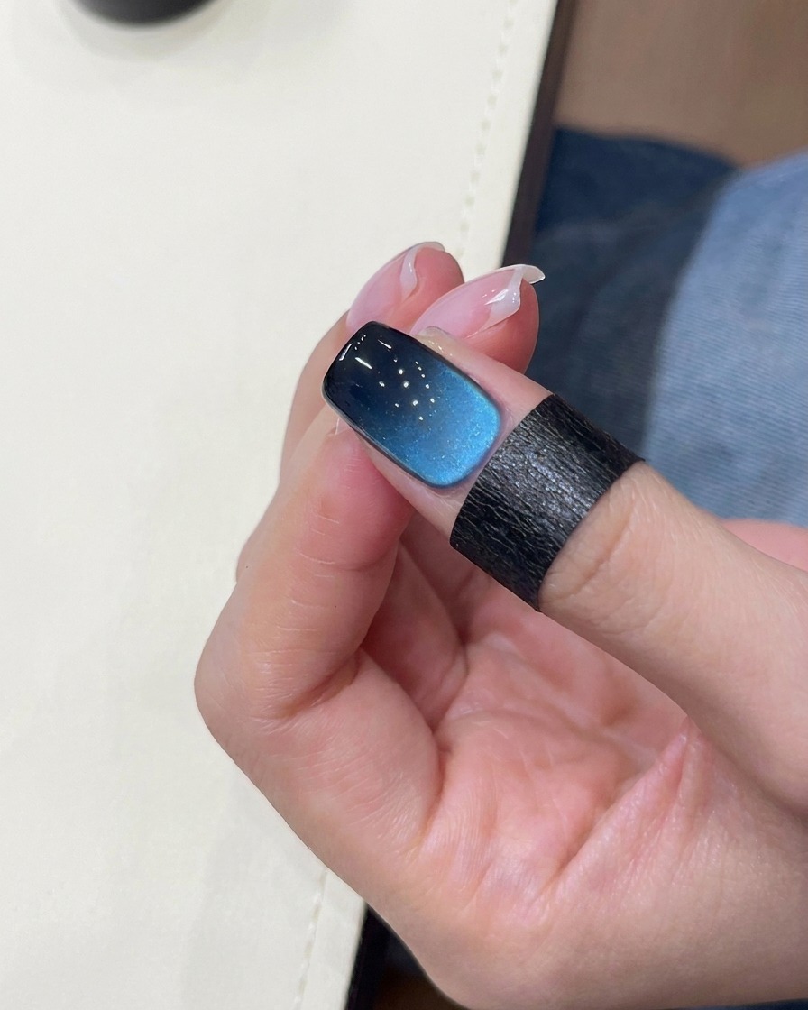 A brush applying black gel to the tip of a nail.