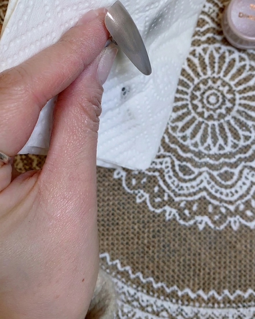 A hand holding the nail tip up to inspect the chrome gradient progress closely.