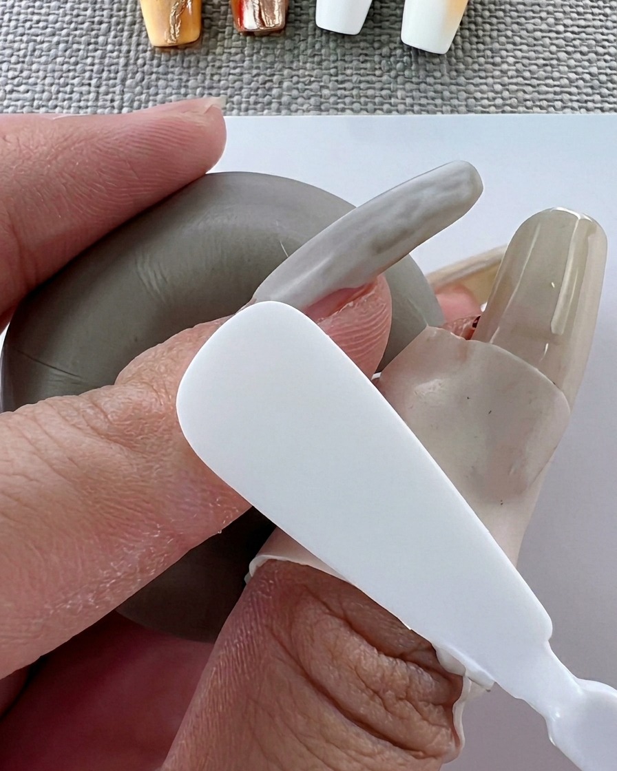 A brush applying smooth white gel polish to the nail surface.