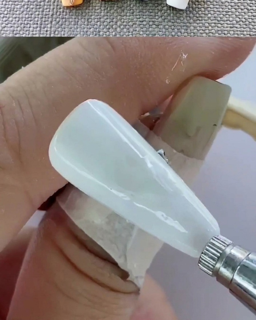 A close-up view of a hand inside a UV lamp curing the nails.