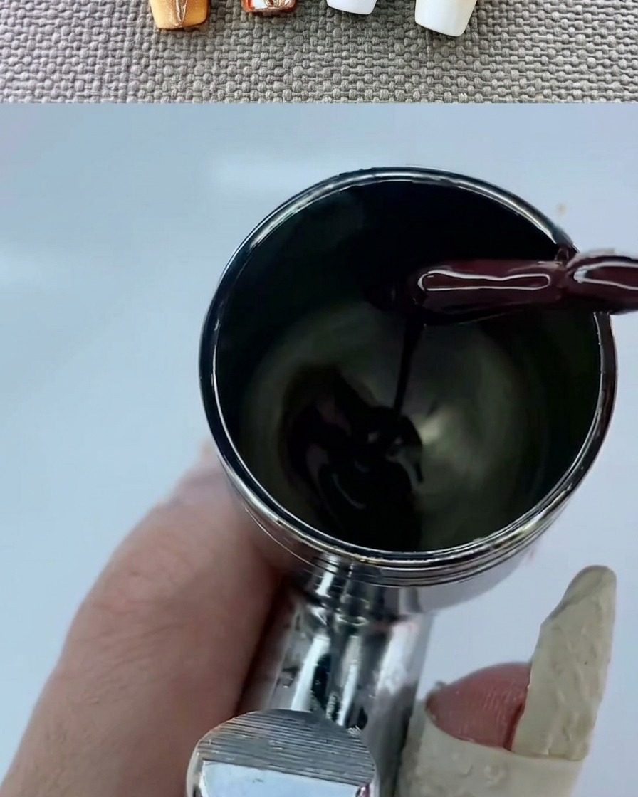 An airbrush tool creating a soft-focus warm gradient on a white-based nail.
