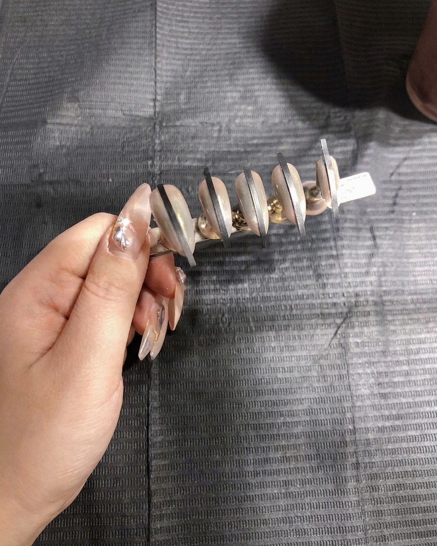 An airbrush gun applying the first coat of white spray gel to the second set of nails.