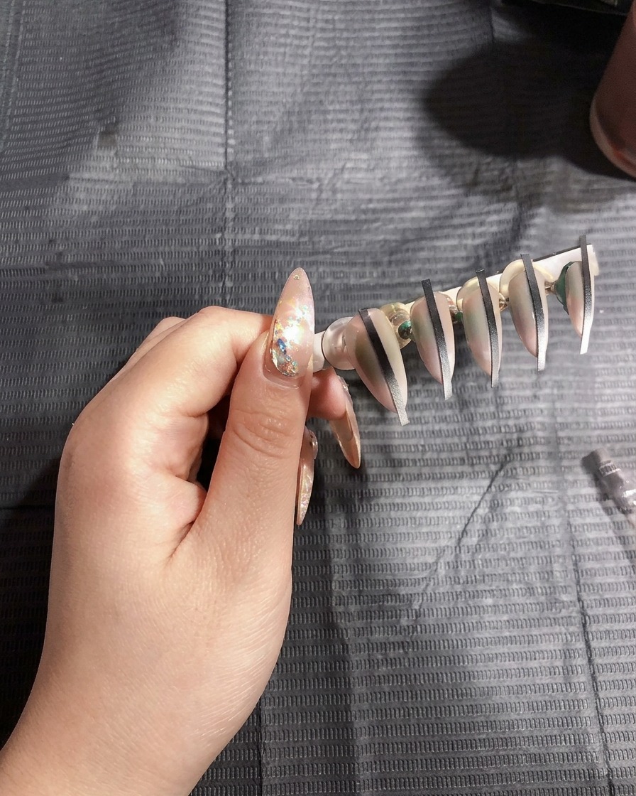 Artificial nails on a stand curing under the bright light of a UV nail lamp.