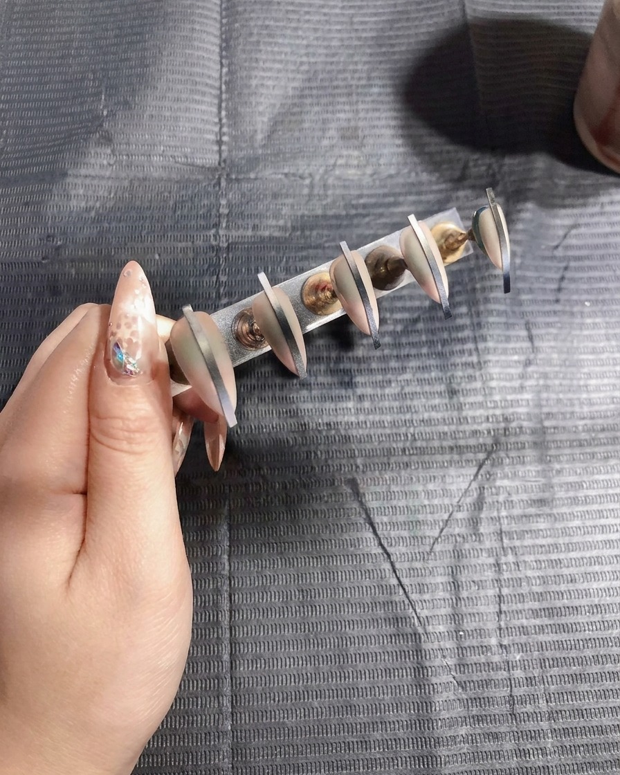 Artificial nails being cured under a UV lamp, signaling the completion of the color application.
