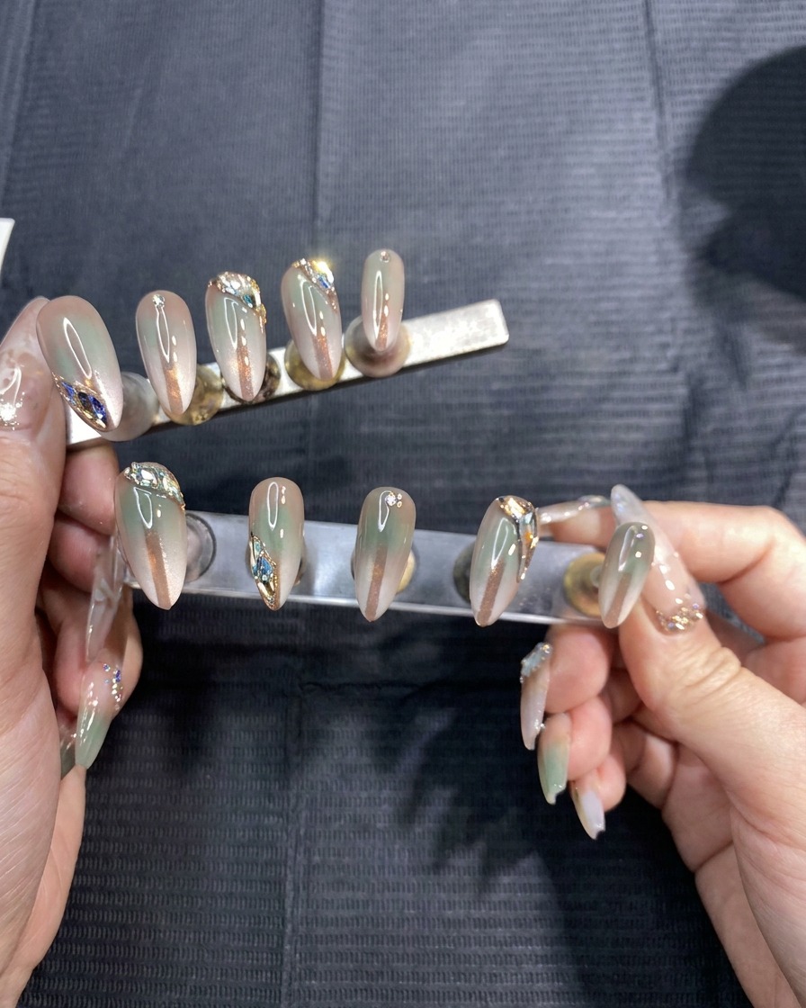A pair of hands carefully removing thin adhesive stencil stickers from a set of gradient-painted false nails.
