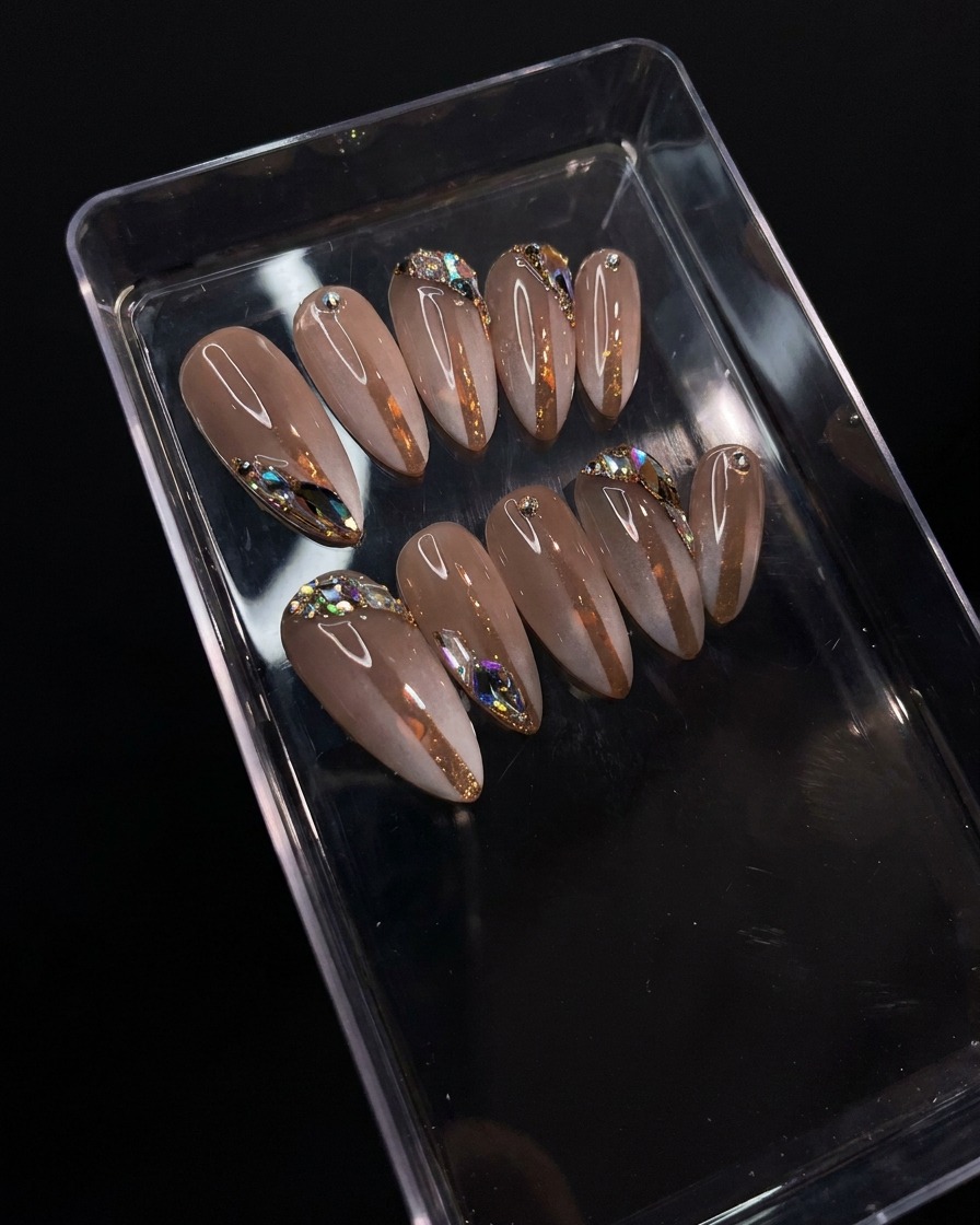 A nail brush applying a clear, glossy top coat over the detailed gradient and rhinestone nail design.