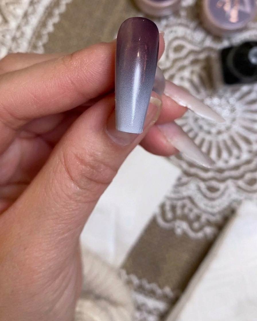 An airbrush applying the final, more intense layer of white gradient to the nail.