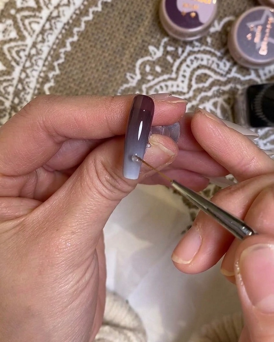 A fine liner brush blending the transition area of the gradient on the nail.
