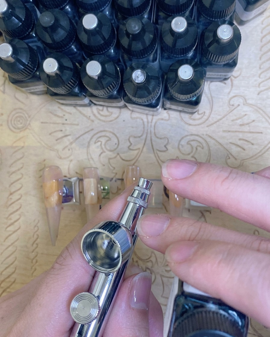 A close-up view of fingers placed inside a professional UV/LED lamp with a purple light visible, curing the manicure.