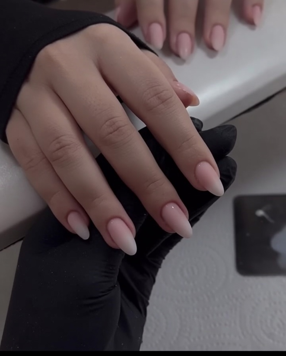A close-up view of a sponge applicator pressing white chrome powder onto the tip of a pinky fingernail.
