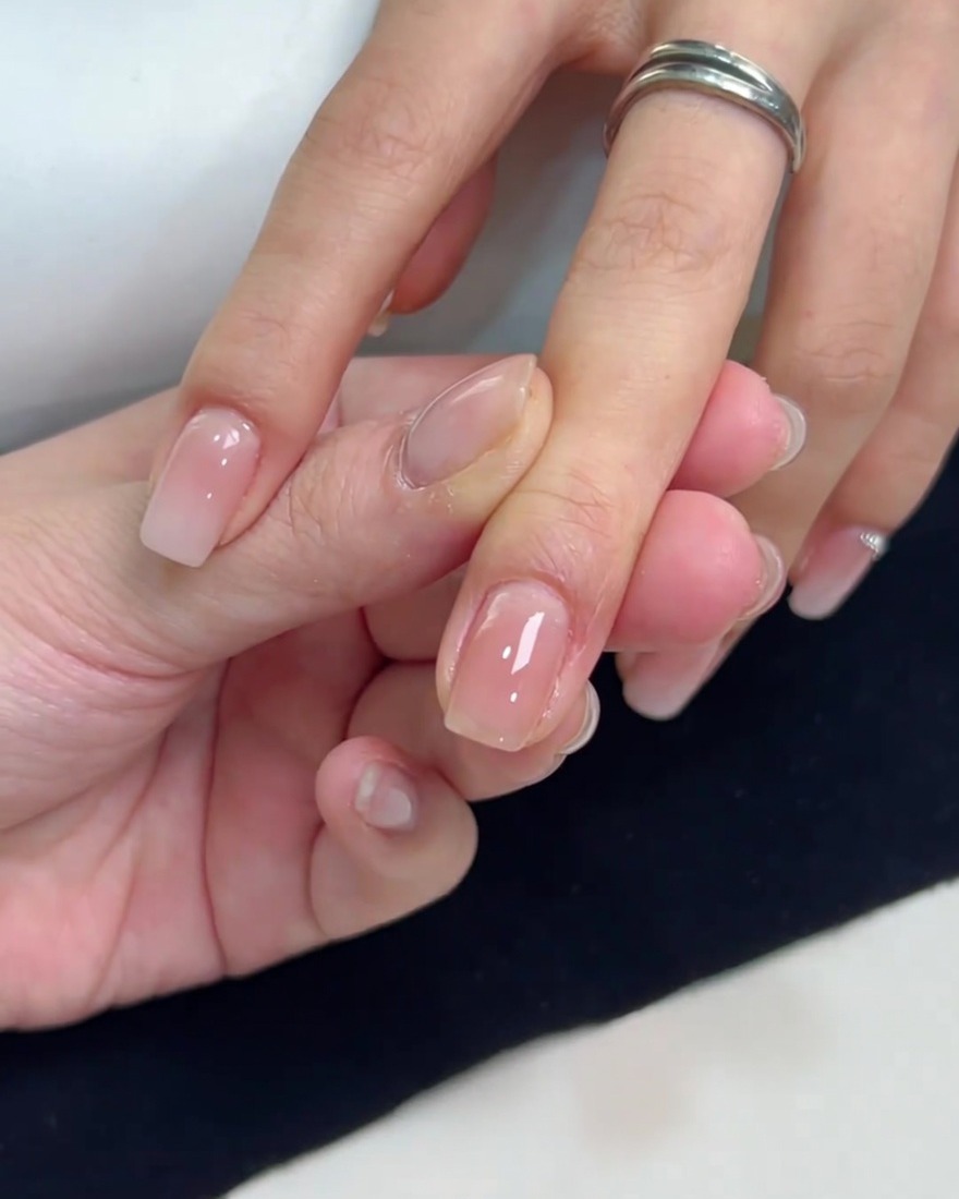 A close-up view of a square nail with a smooth, glossy coat of sheer nude gel polish applied evenly.