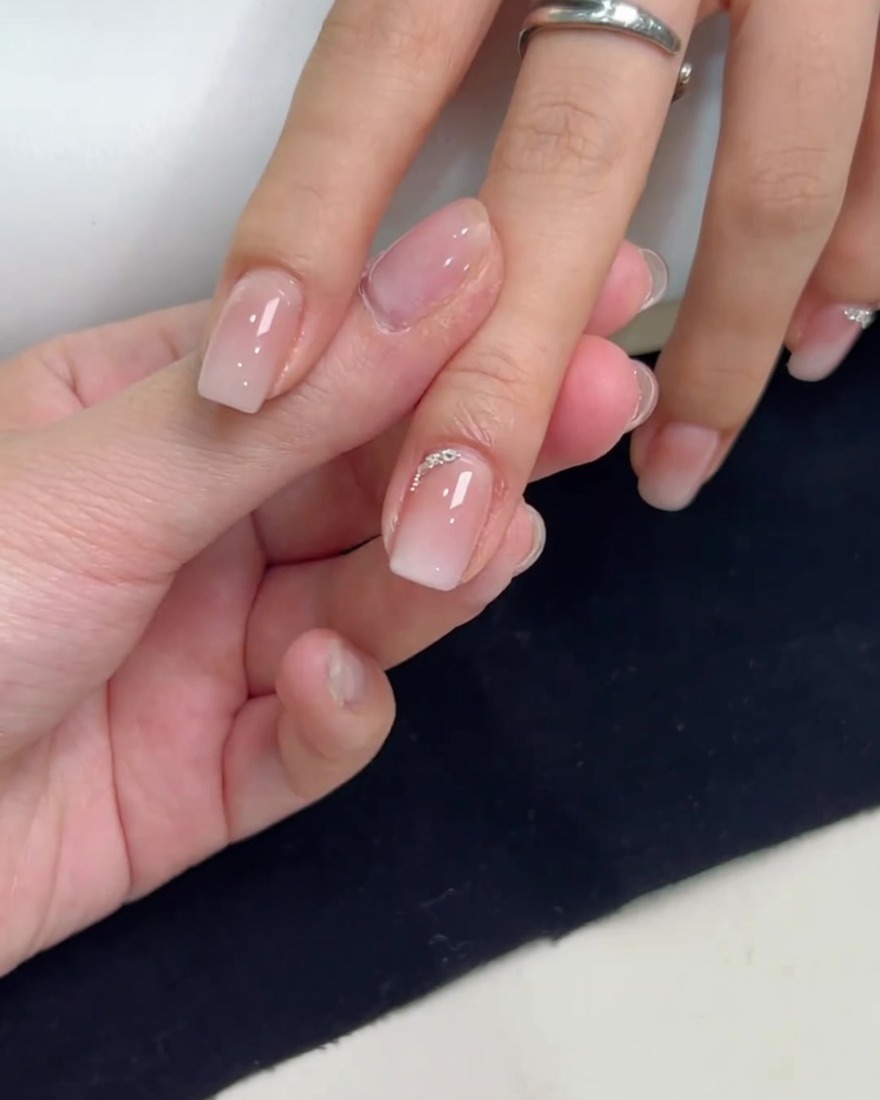 A square gradient nail decorated with a delicate row of small silver rhinestones and tiny silver steel beads along the cuticle curve.