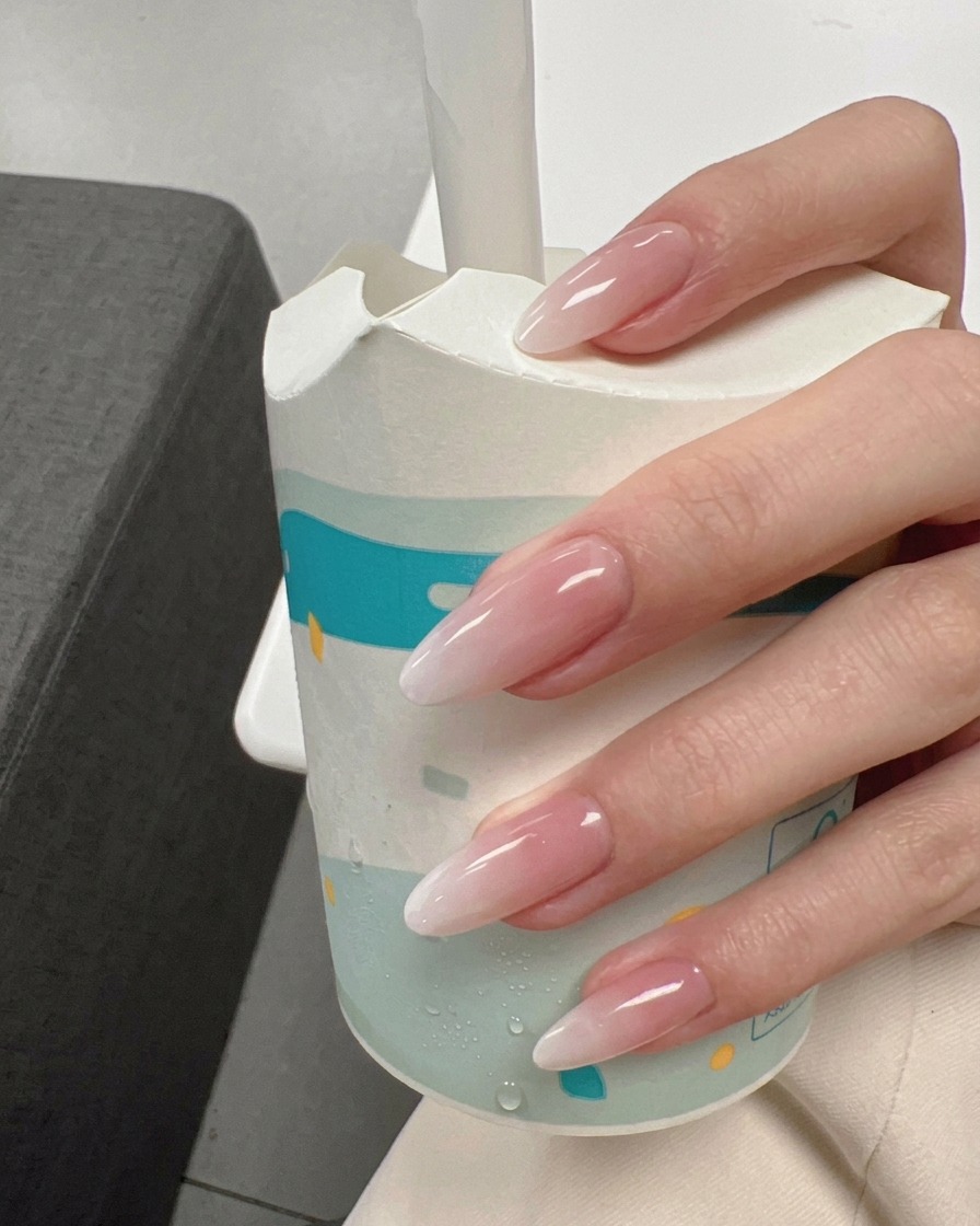 Milky white gel being applied from the middle of the nail to the tip.