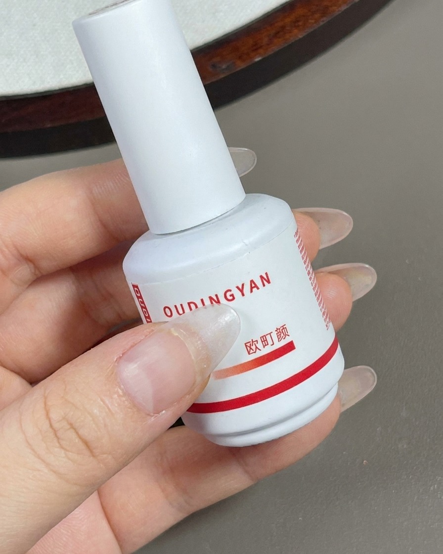 A brush applying a layer of sheer contour nude gel over the entire nail surface.