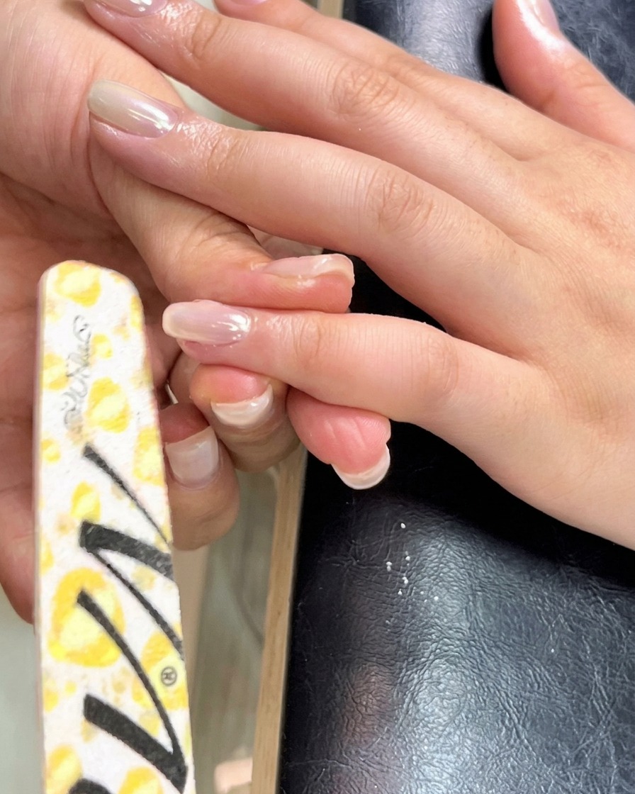 A thin liner brush spreading construction gel evenly toward the cuticle and sidewalls of the nail.