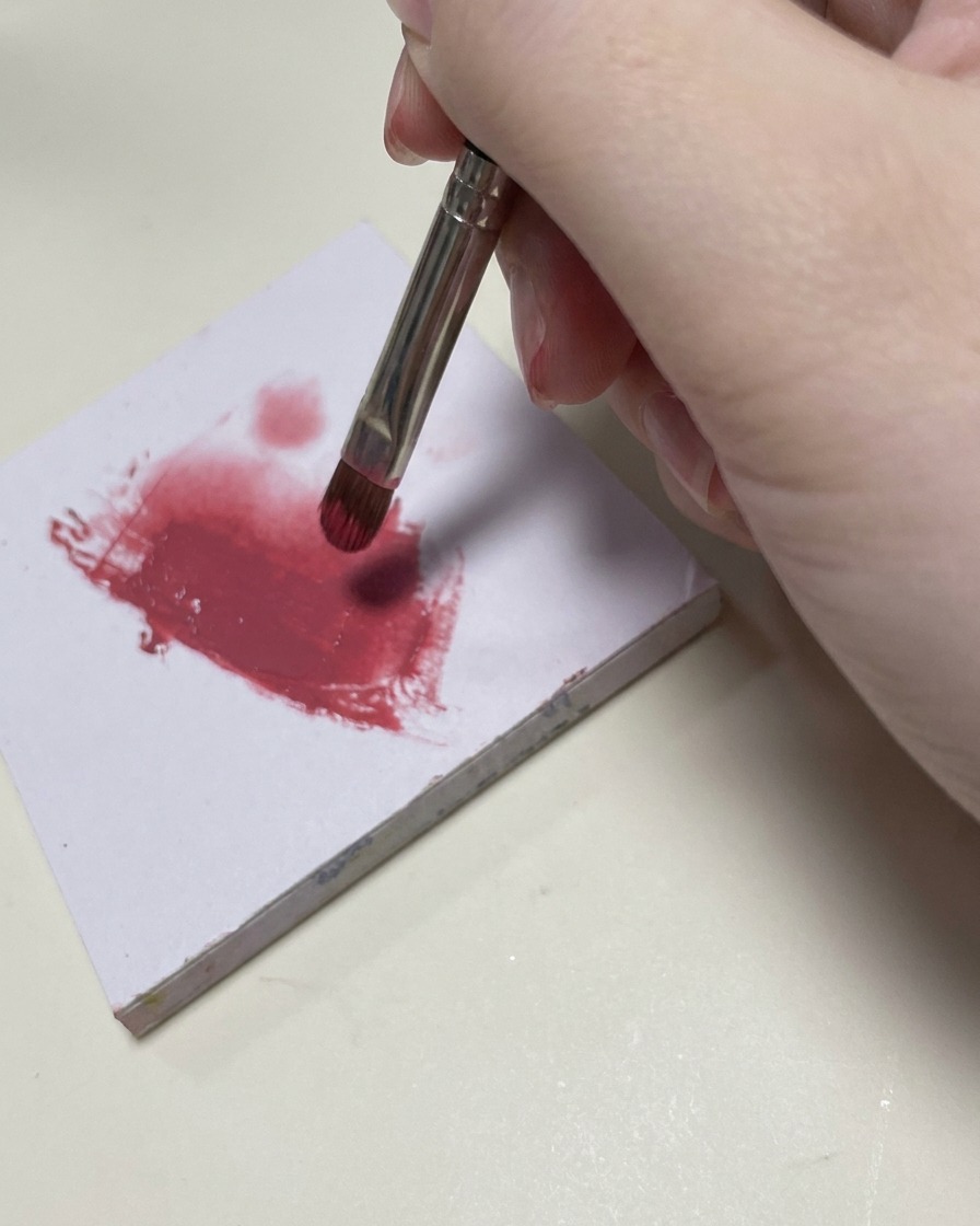 A small nail art brush blending pink gel polish onto the middle section of the nail.