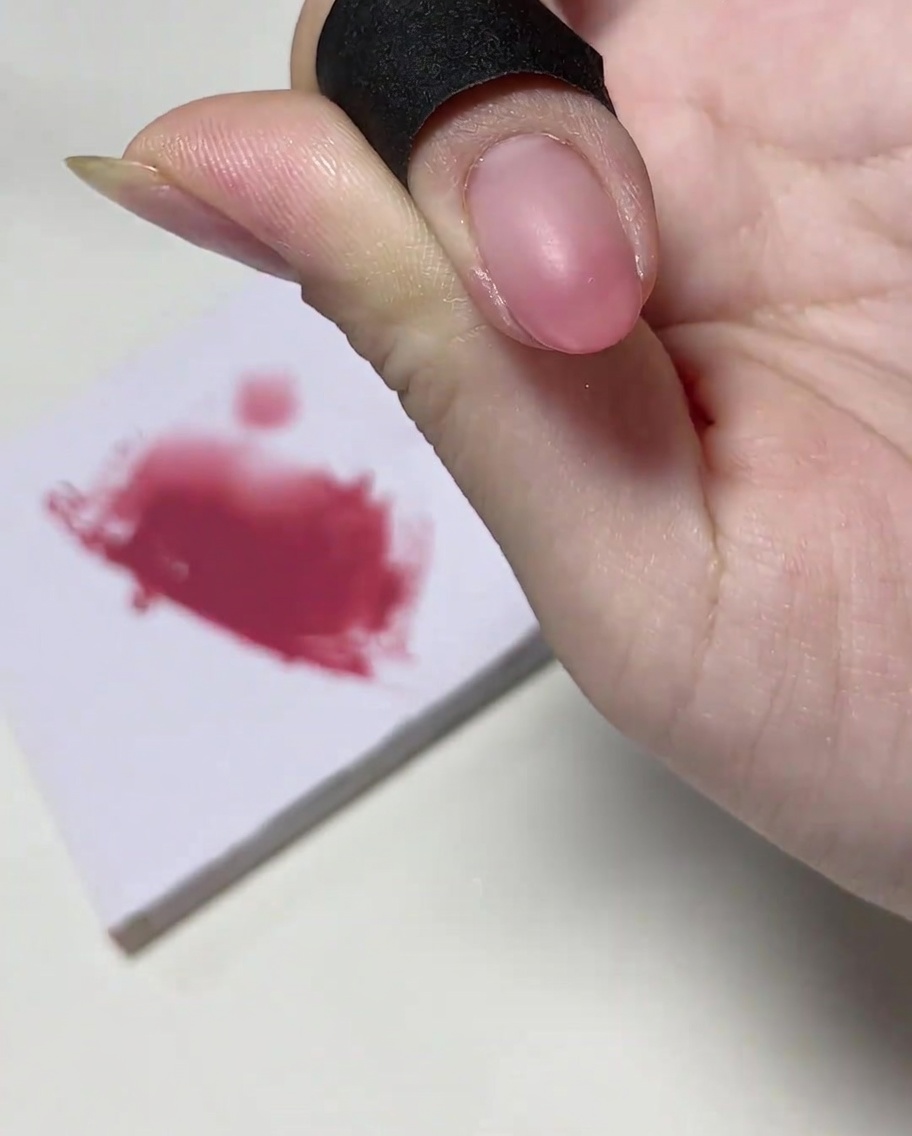 A nail brush adding a concentrated amount of pink gel polish to the very tip of the nail.