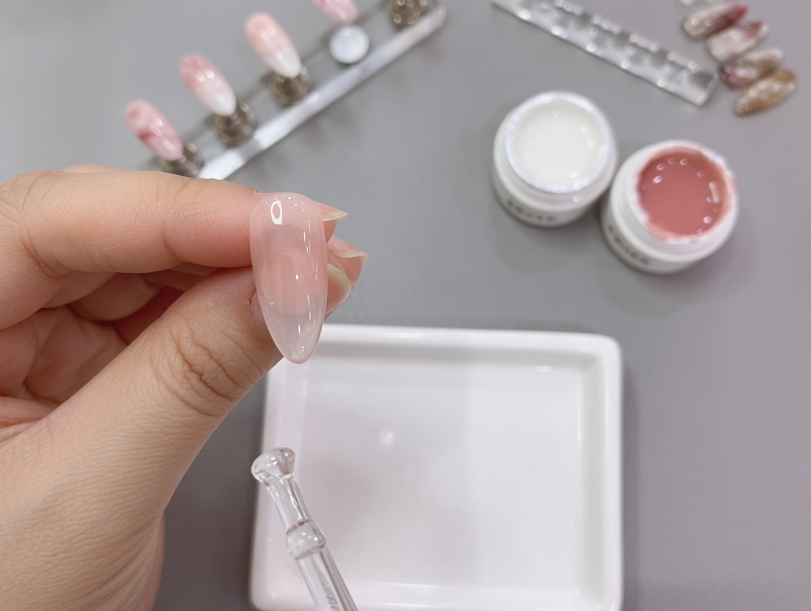 A close-up view of a hand with a completed nude-to-white gradient nail design being placed under a UV lamp for the final cure.
