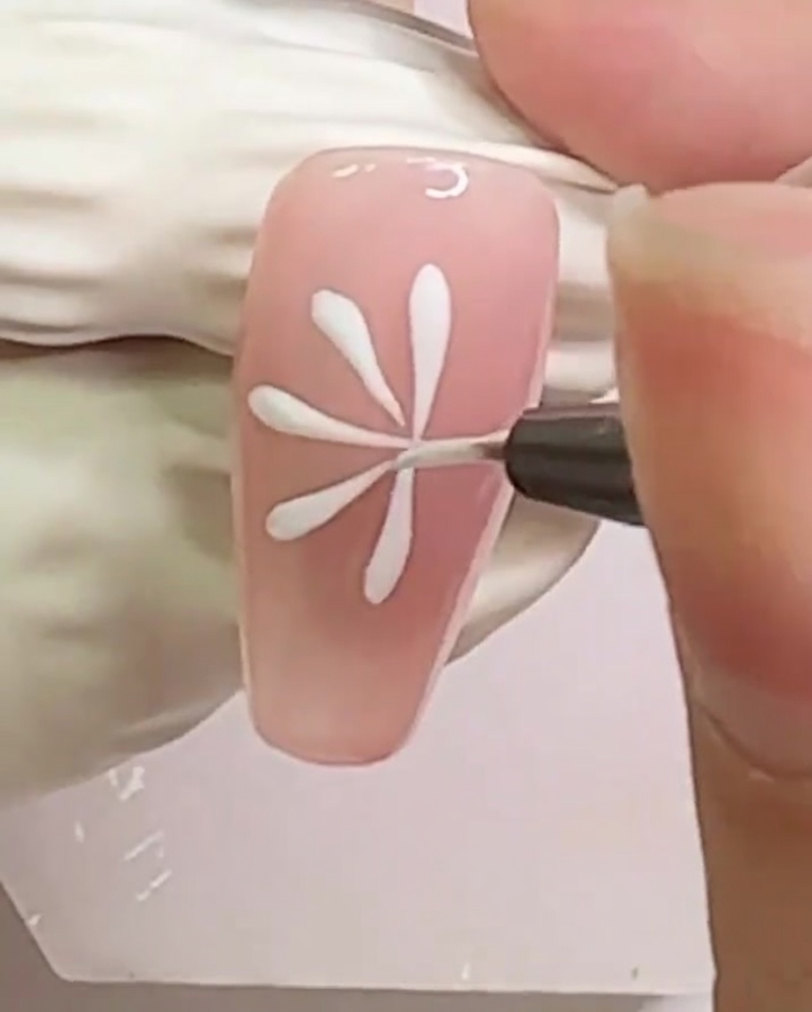 A nail featuring a dense pattern of white radial lines for the daisy.