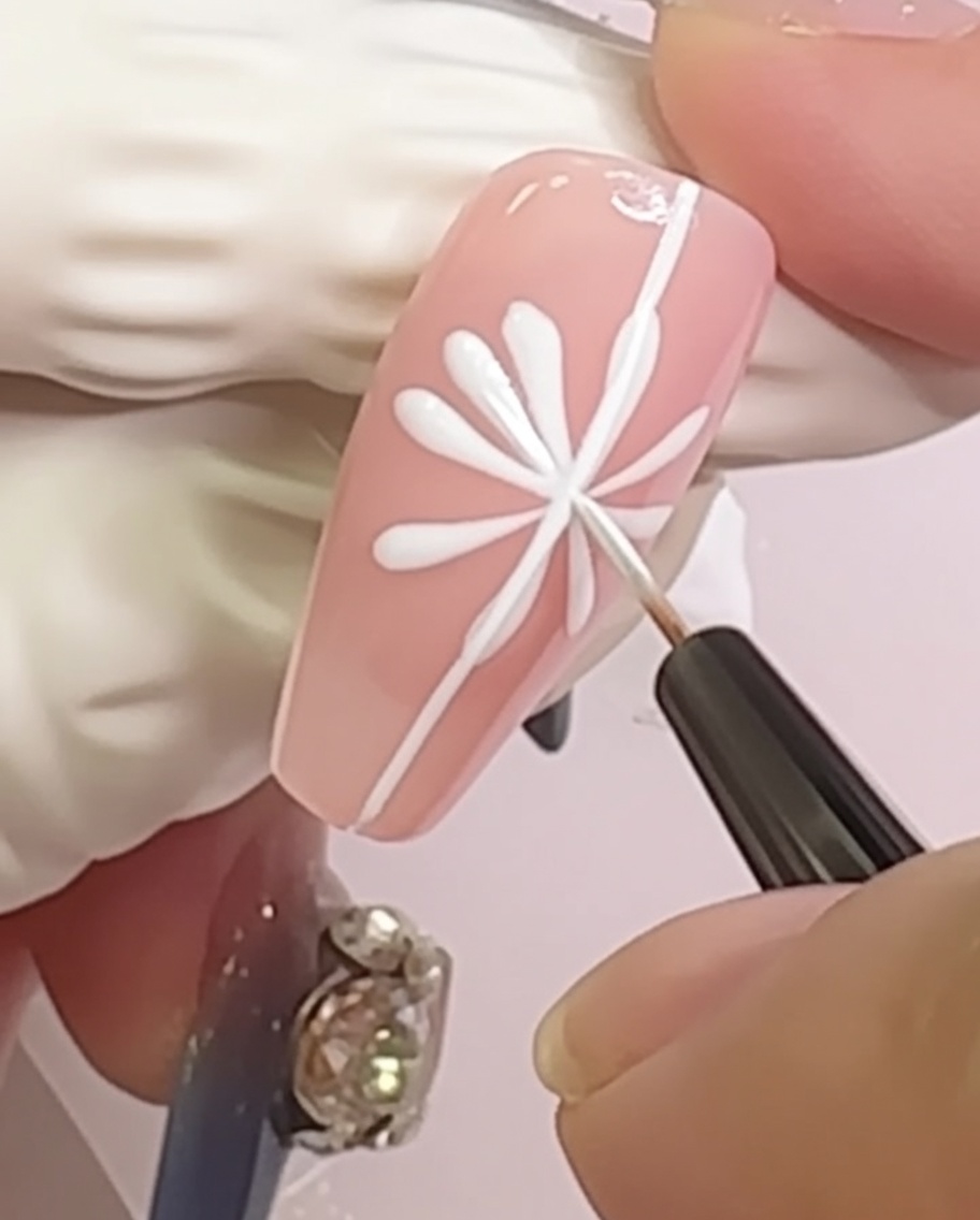 A nail showing a daisy design with small, rounded petal shapes added to the tips of the radial lines.