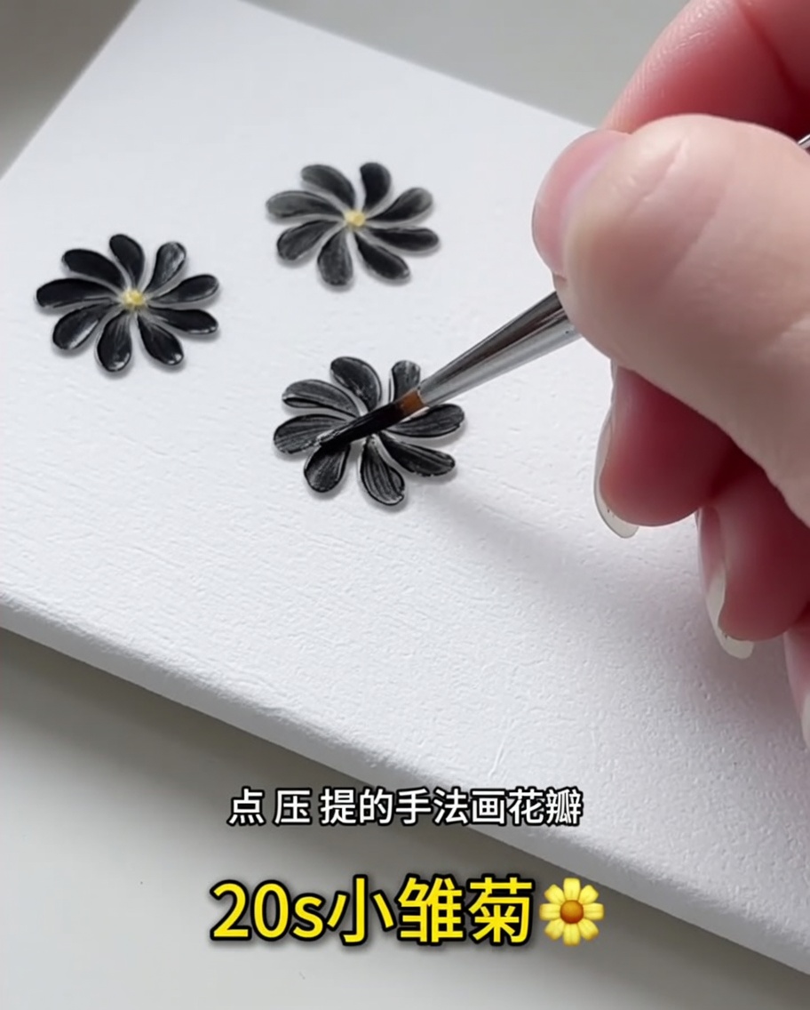 A close-up view of a fine liner brush applying a single black gel petal onto a white surface.
