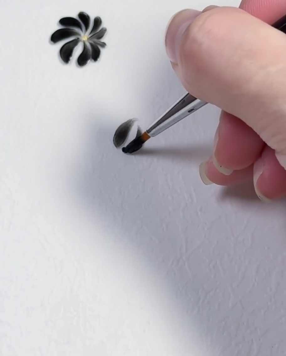 A brush stroke forming the third black petal of a daisy design.
