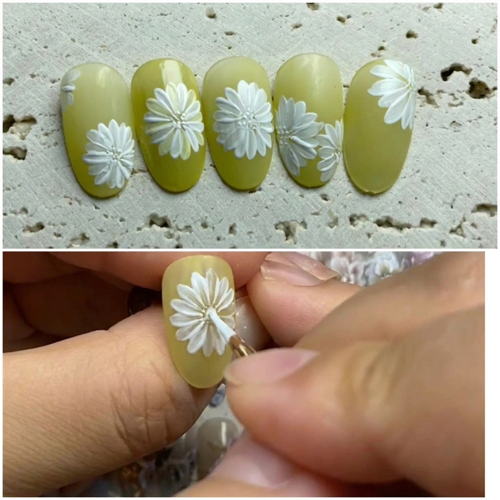A close-up view of a nail art design on a light green base, where a brush is adding white petals between the existing ones to complete a daisy flower.