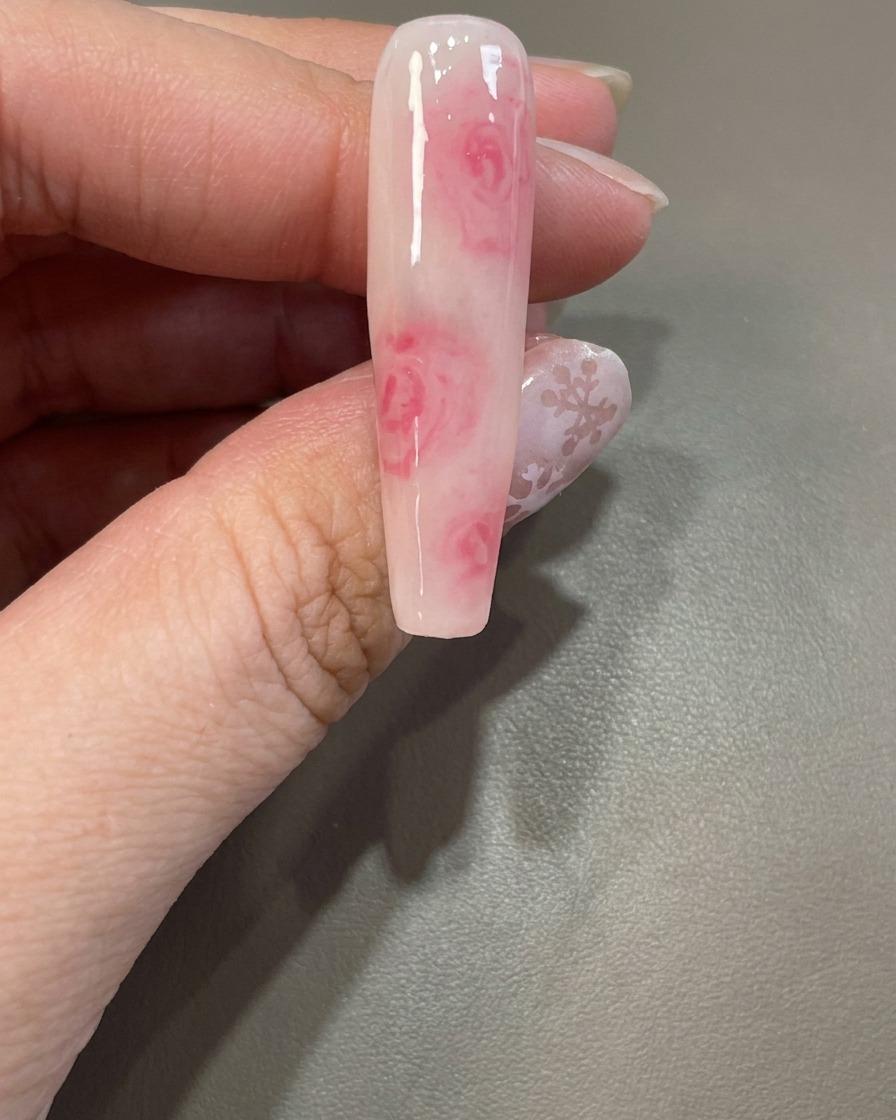 A brush reapplying a clear blooming gel layer over an existing nail design.