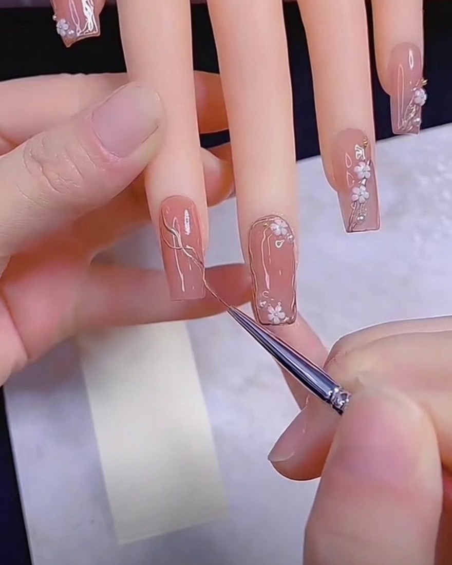 Detail brush applying metallic gel to a nude nail.