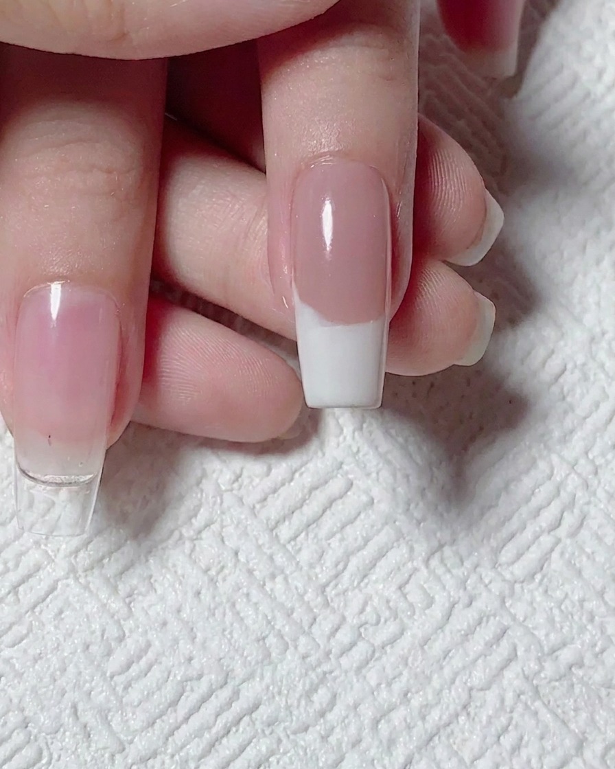 A top-down view of a completed white French tip design on a nude base, ready for nail art.