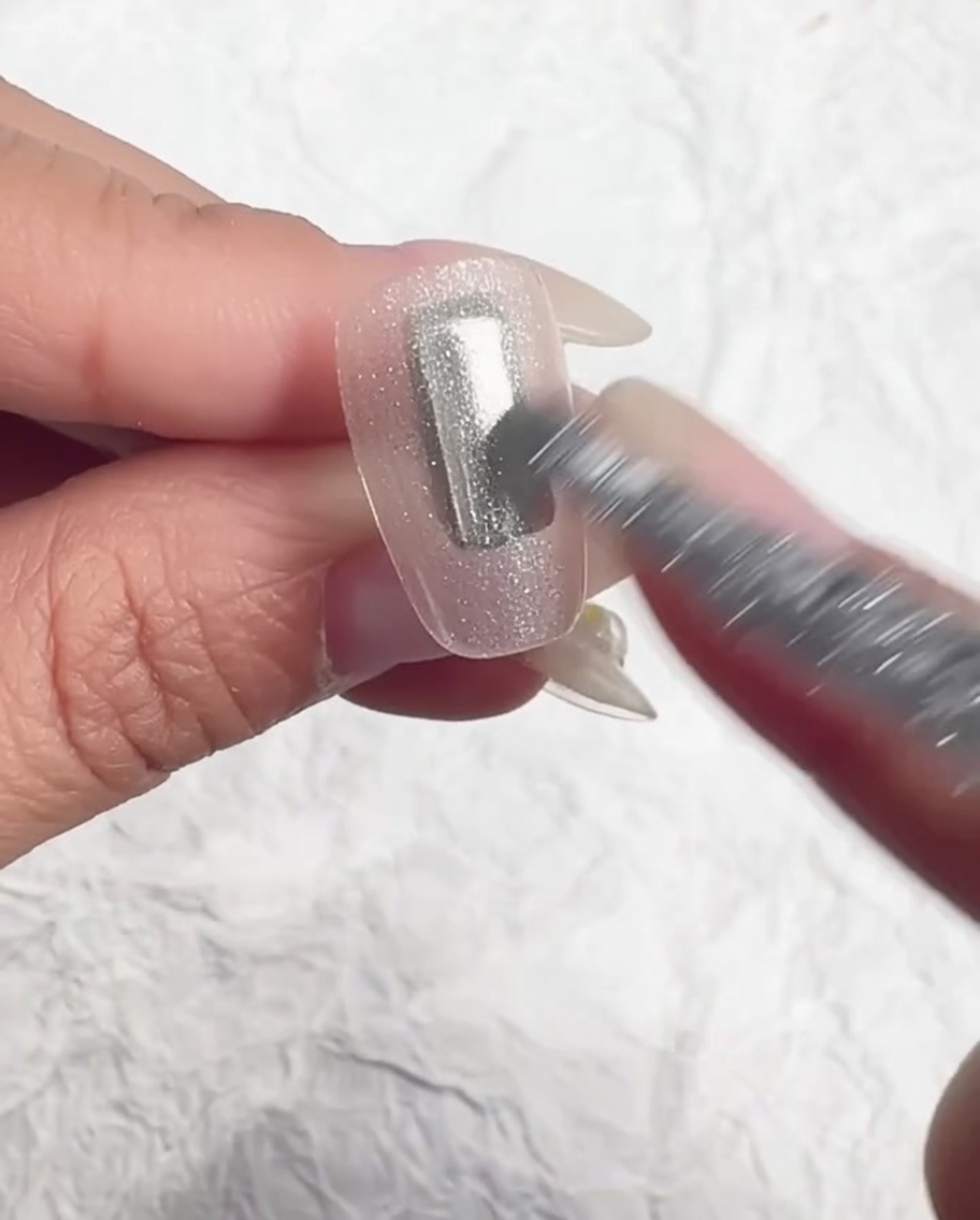 A brush evening out the ice-translucent gel on the nail.