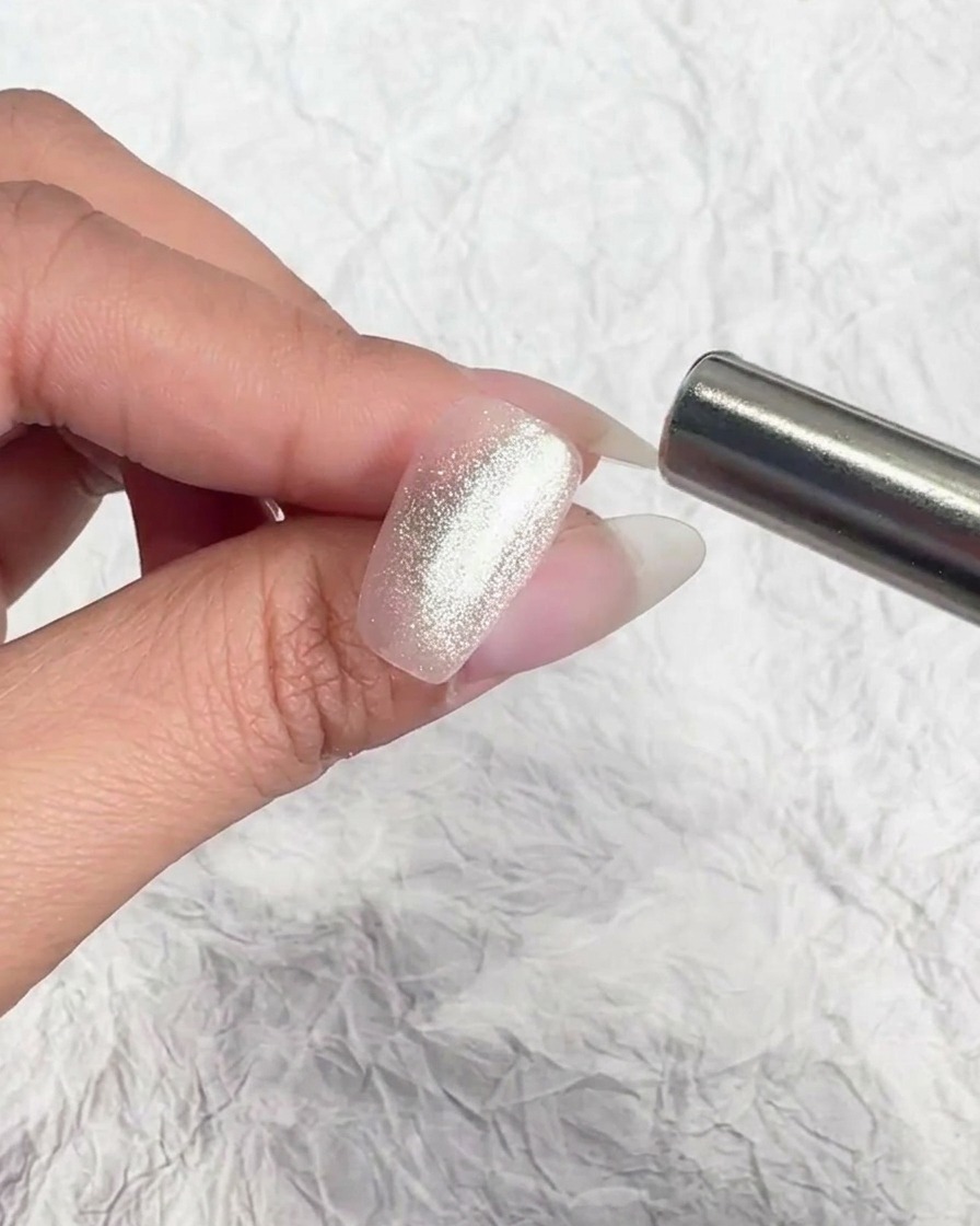 A metallic magnet tool held near a nail to manipulate the magnetic particles.