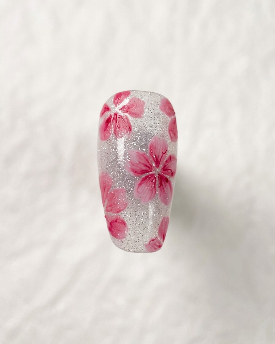A close-up shot of a completed cherry blossom nail art design, highlighting the dark, fine details in the center of the flowers.